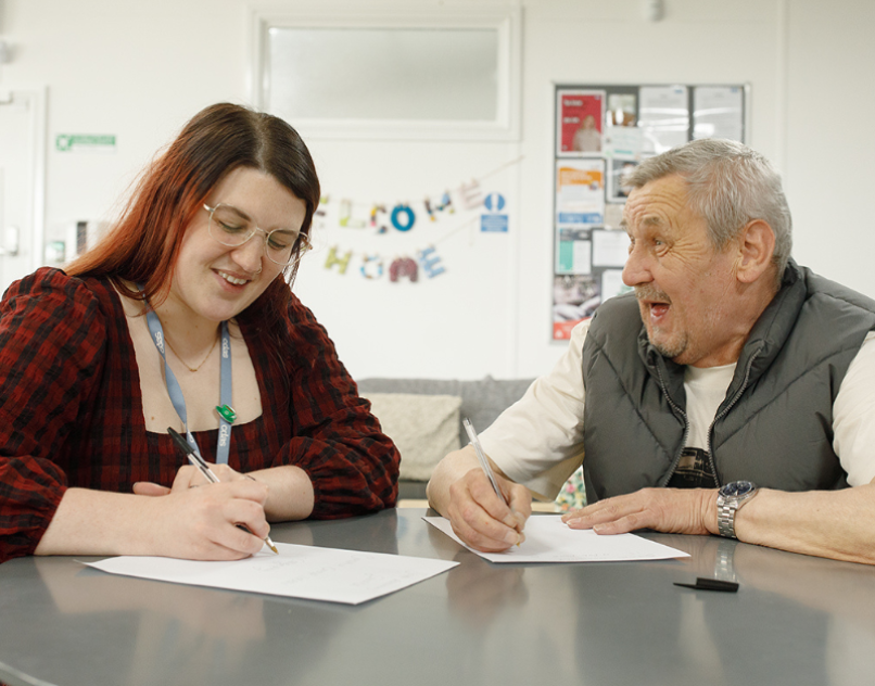 CDAS staff member sitting with a client, filling out forms together during a support session