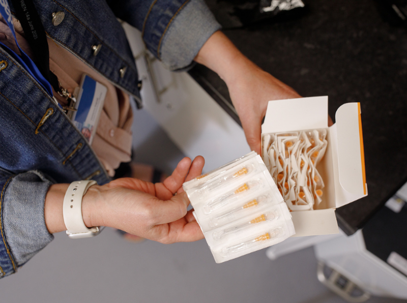 Close up of a person holding a box of sterile syringes