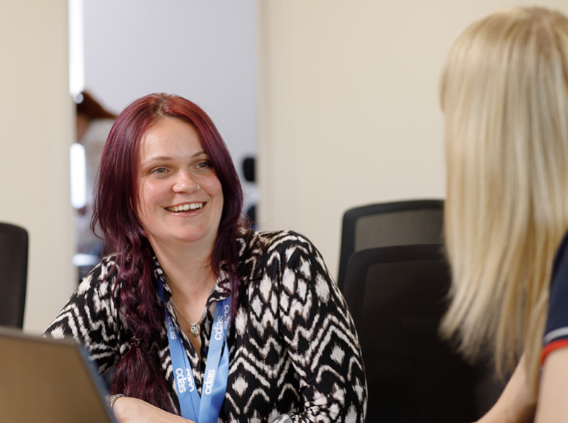 CDAS staff member smiling and talking with another woman, whose face is turned away from the camera
