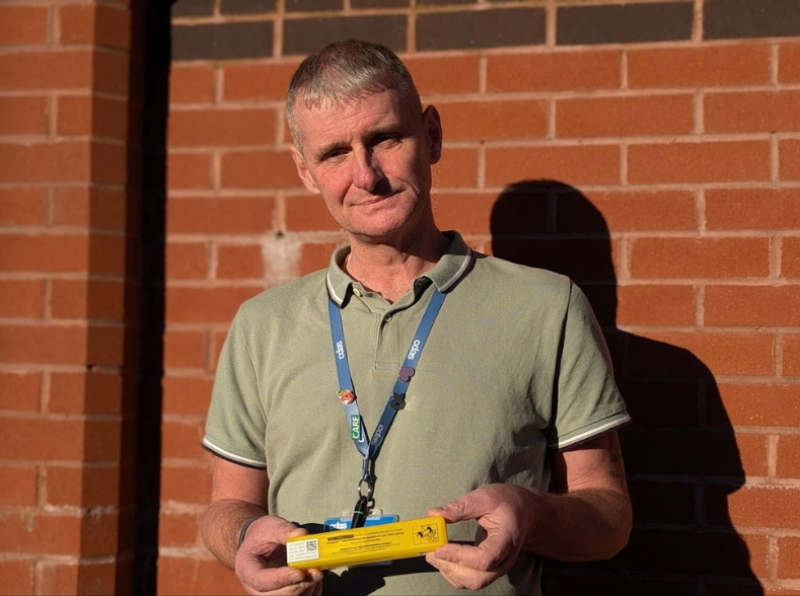 Stephen Griffiths, standing in front of brick wall, looking at the camera and holding a naloxone kit