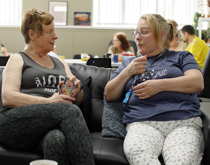 Two women sitting on a sofa having a friendly conversation