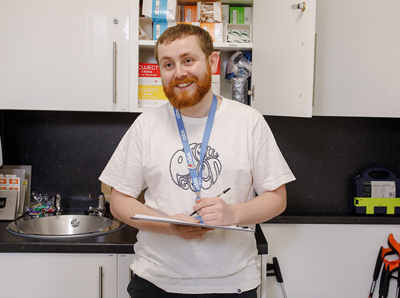Smiling staff member holding a clipboard in a clinical room at CDAS, representing support for professionals